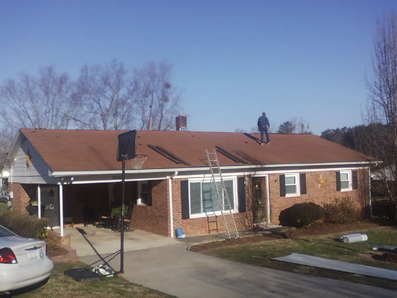 Roofer stripping a shingle roof on a brick ranch before metal panels in Nauvoo