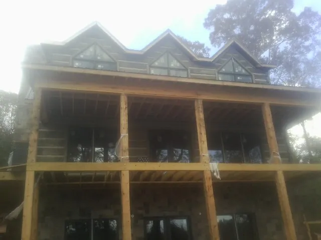 Dormers and porch framing on a large log home under construction — Roof Coating work by our crew in Nauvoo