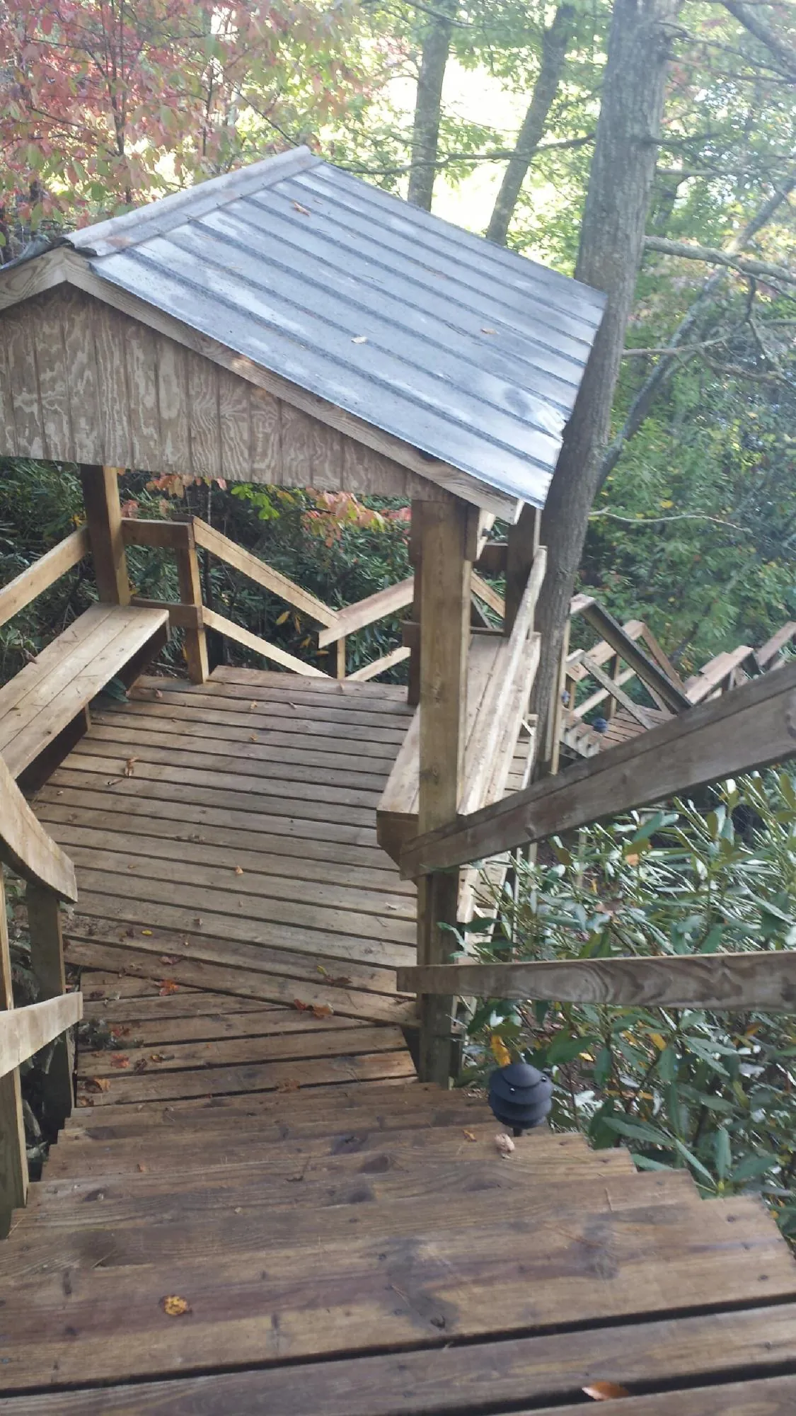 Metal roofed shelter over wooden steps on a wooded walkway — Skylight Repair & Installation work by our crew in Nauvoo